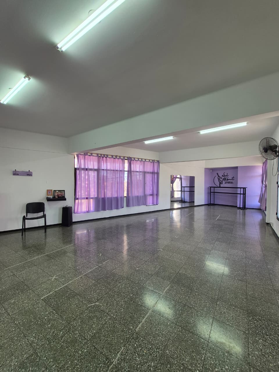 Salón de clases con barras, espejo y cortinas lilas